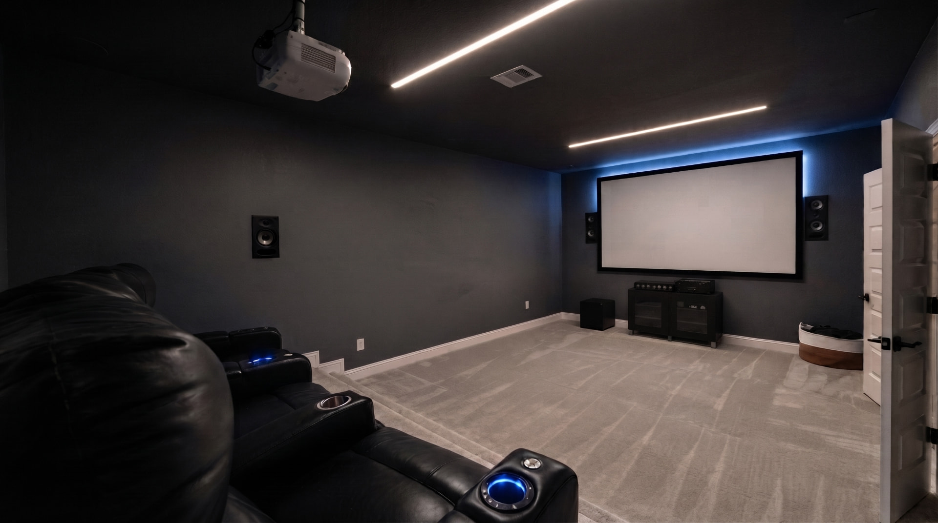 Residential home theater by Sound & Scene with tiered seating, acoustic treatment, and projection screen